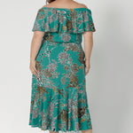 Back view of a woman wearing the Myla dress in Jade Safari off shoulder frill neck style. Side pockets and frill hem. Made in Australia and size inclusive for women size 8-24. 
