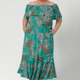 Plus sized woman wears Australia Made maxi dress in jade colour. Frill bodice and frill skirt dress adds fluid and feminine movement for off duty weekend statement styling. Shop jade safari collection at Leina & Fleur in size 8-24.