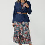 Worn on one shoulder. A woman wears the Myla dress in Whimsy an off shoulder frill neck style. Side pockets and frill hem. Made in Australia and size inclusive for women size 8-24. Styled back with a Denim Blazer.