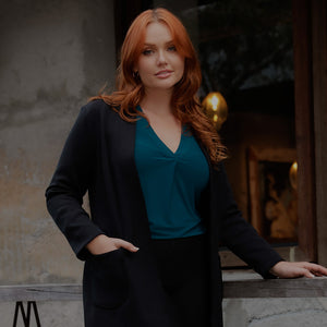 Cover image for luxury clothing brand, Australian-made Leina & Fleur's winter lookbook with a woman wearing a V-neck top in teal blue jersey under a long black jacket.