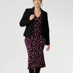 Petite height woman wears workwear dress with thoughtfully placed ruched details at the front, back, and along the sleeves. Which ad gentle shaping and a touch of textural interest, while enhancing comfort and ease of movement.