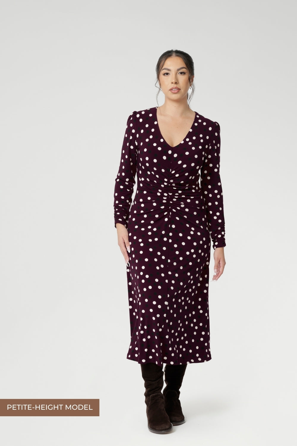 Petite height woman wears workwear dress with thoughtfully placed ruched details at the front, back, and along the sleeves. Crafted from Australian made dry touch jersey. 
