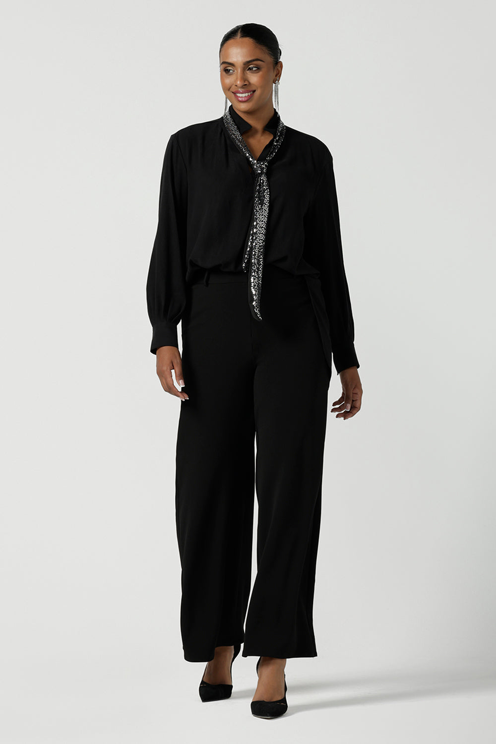 A size 10 woman wears the Silver Neck tie Silver Sequin Ellis and made in Australia size 8-24, Styled back with a shirt in black and black scuba crepe pants.