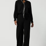 A size 10 woman wears the Silver Neck tie Silver Sequin Ellis and made in Australia size 8-24, Styled back with a shirt in black and black scuba crepe pants.