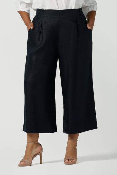 Close up of a corporate woman size 16 wears a linen Nik Pant in Midnight navy back with a white Arley shirt. A tailored pant with buttons and pleat front with a zip at the side. Petite height friendly. Linen fabric is a natural breathable material. Made in Australia for women size 8 - 24.