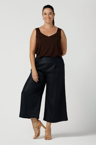 A size 12 curvy woman wears a Midnight linen Nik Pant in linen. Side zip and button front with pleats. Styled back with Eddy cami in Cocoa. Made in Australia for women size 8 - 24.