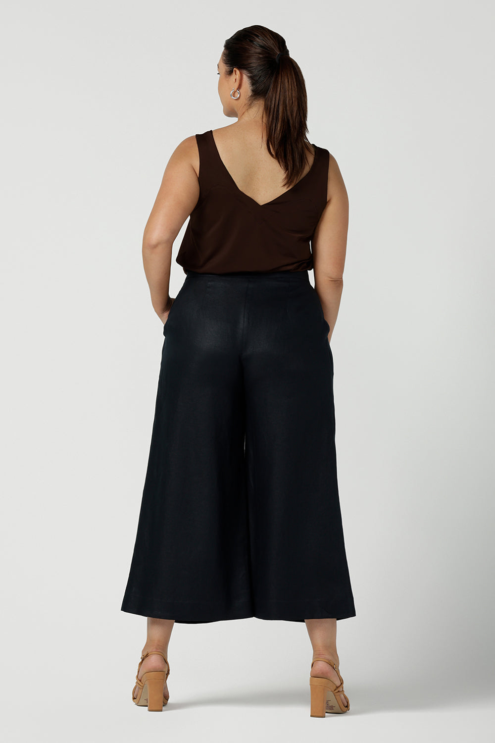 Back view of a size 12 curvy woman wears a Midnight linen Nik Pant in linen. Side zip and button front with pleats. Styled back with Eddy cami in Cocoa. Made in Australia for women size 8 - 24.