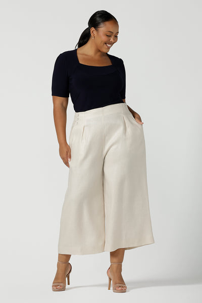 Size 16 woman wears the Nik Pant in Parchment Linen. A high waist tailored pant with buttons and pleats at the front. Made in natural linen a breathable fibre that is great for the warmer months. Styled back with a black Berni top. Made in Australia for women size 8 - 24.