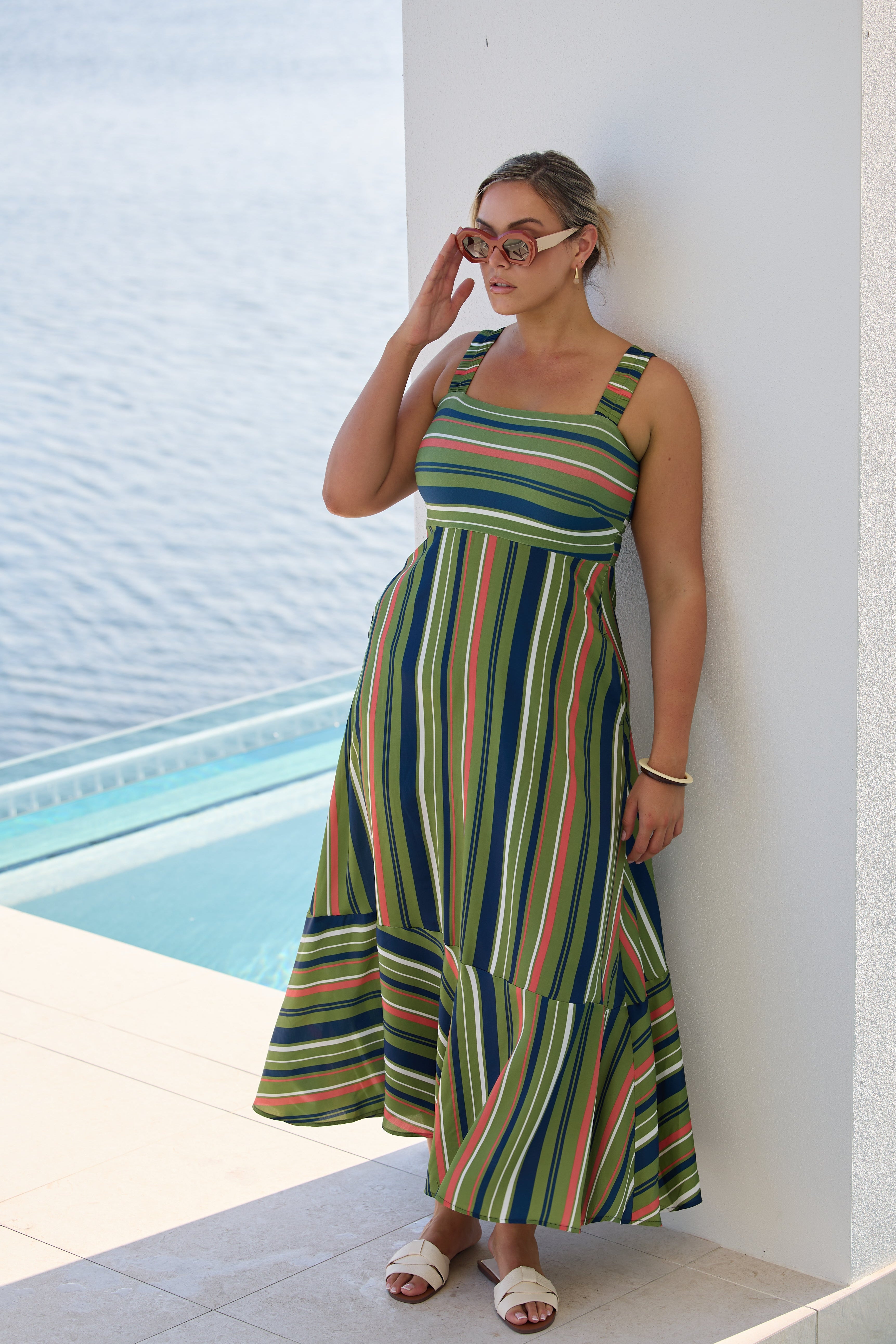 Woman in a striped dress standing by a poolside.