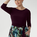 The flattering fit-and-flare silhouette is designed to suit all body shapes, with the option to wear it with or without its matching belt for versatile styling. A double-layered bodice offers added coverage and comfort, while ¾ sleeves and a gently rounded neckline create a refined, feminine finish. The midi-length A-line skirt features a bold abstract print in tones of green, blue, and plum—eye-catching yet timeless.