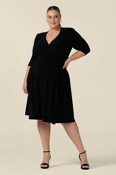 A knee length wrap dress in black jersey looks elegant for evening and occasion wear, size 18. Shown for plus sizes, this 3/4 sleeve event dress is made in Australia in dress sizes 8 to 24.