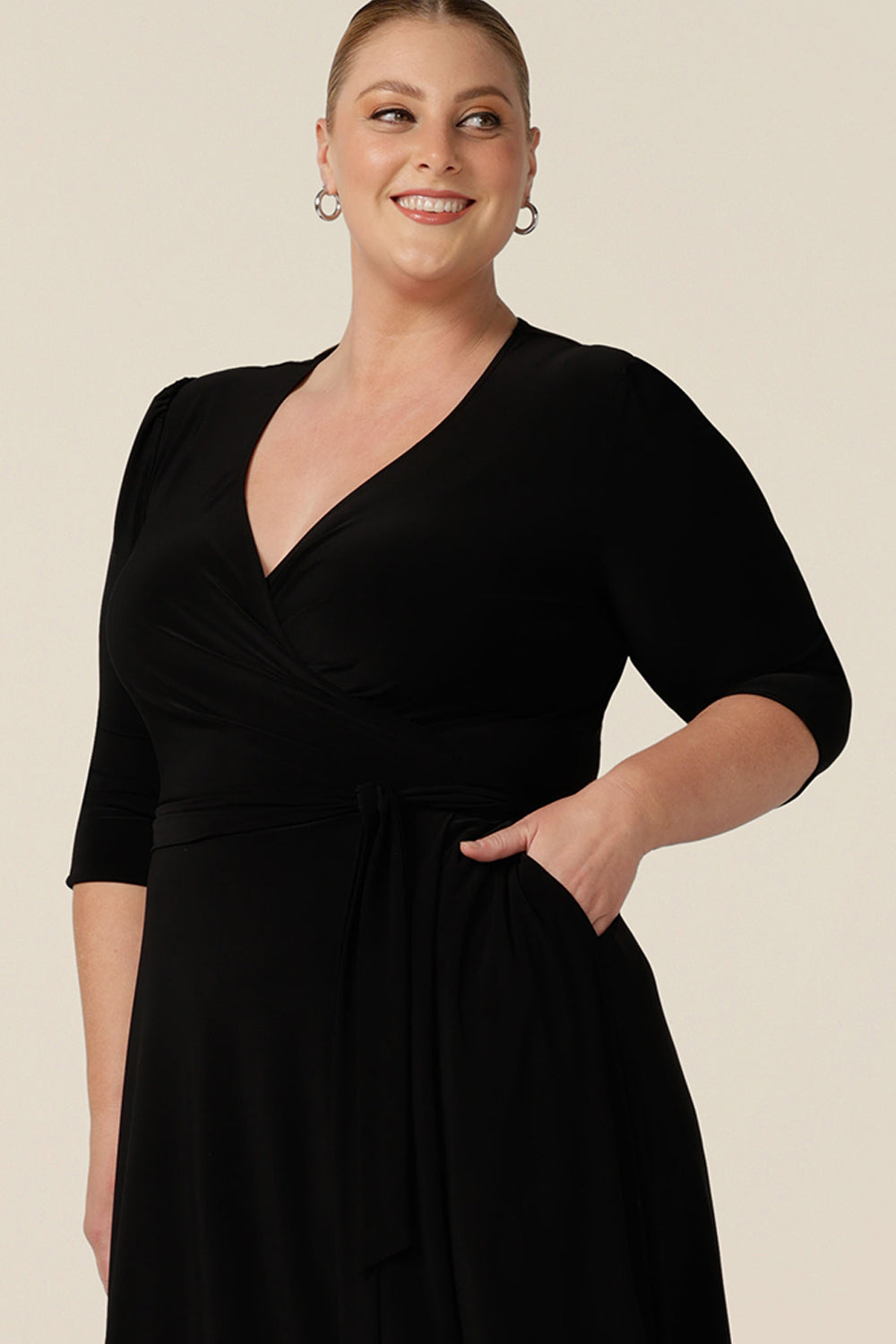 Close up of the neckline of a knee length wrap dress in black jersey, elegant for evening and occasionwear. Shown for plus sizes, this 3/4 sleeve event dress is made in Australia in dress sizes 8 to 24.