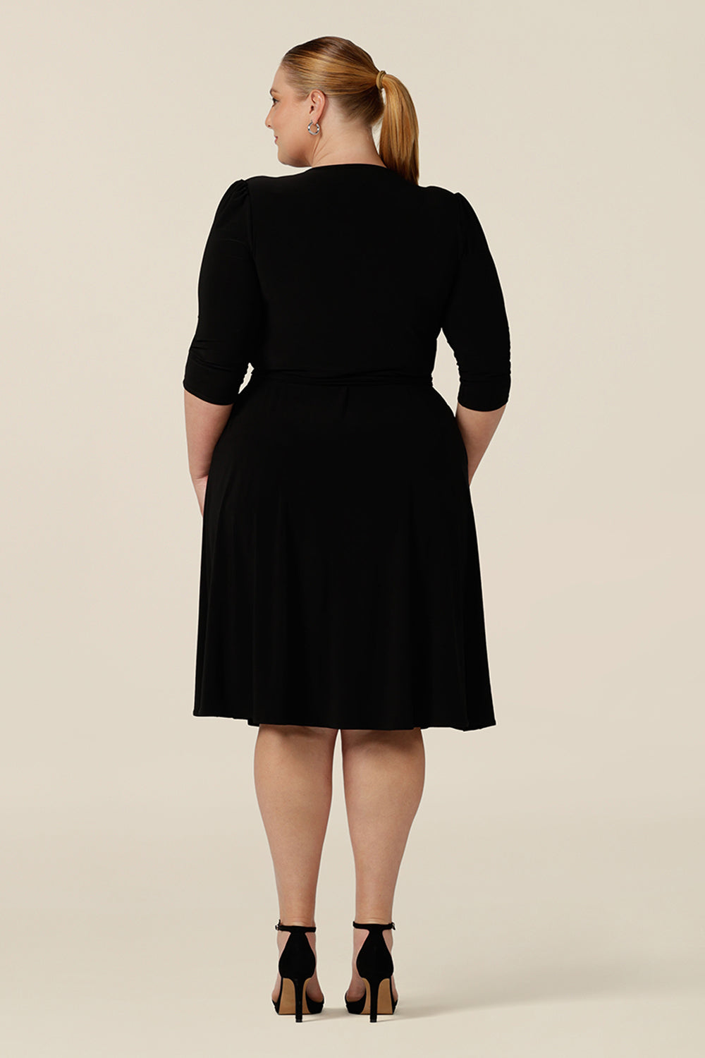 Back view of a good going out dress for plus size women. This knee length wrap dress in black jersey has 3/4 sleeves and pockets.  Shown for plus size women, shop made in Australia dresses in sizes 8 to 24.