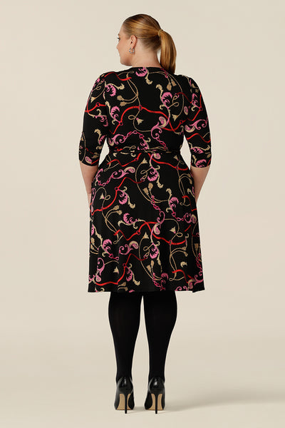 Back view of a knee length wrap dress in rococo print jersey looks sassy for work and occasionwear. Shown for plus sizes, this 3/4 sleeve wrap dress is made in Australia in dress sizes 8 to 24.