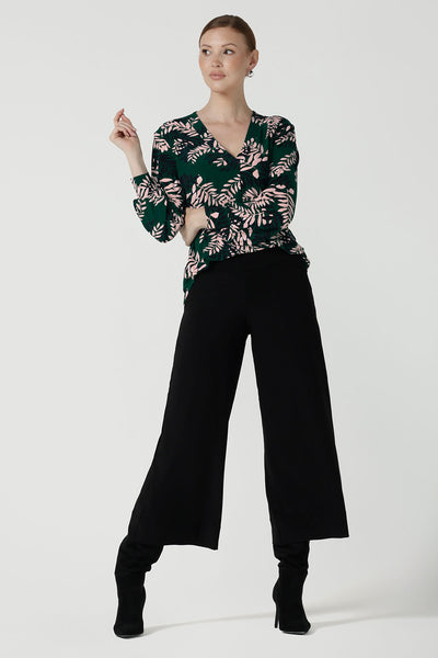 A size 10 woman wears the Paeton Top in  Alpine Fern. Styled back with the Bradley Pant in Black. A wide leg pant in black styled back with boots. Made in Australia for women size 8 - 24. 