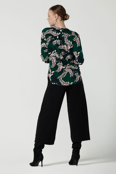 Back view of a size 10 woman wears the Paeton Top in Alpine Fern. Styled back with the Bradley Pant in Black. A wide leg pant in black styled back with boots. Made in Australia for women size 8 - 24.