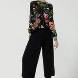 Back view of a size 10 woman wears a jersey work top called the Paeton in Bloomsbury print. Long sleeves with cuff detailed and made in Australia for women size 8-24. Styled back with slim fit comfortable work pants  Bradley culottes.