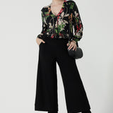 Front view of a size 10 woman wears a jersey work top called the Paeton in Bloomsbury print. Long sleeves with cuff detailed and made in Australia for women size 8-24. Styled back with slim fit comfortable work pants Bradley culottes.