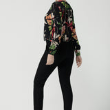 Back view of a size 10 woman wears a jersey work top called the Paeton in Bloomsbury print. Long sleeves with cuff detailed and made in Australia for women size 8-24. Styled back with slim fit comfortable work pants Broolyn in black. 