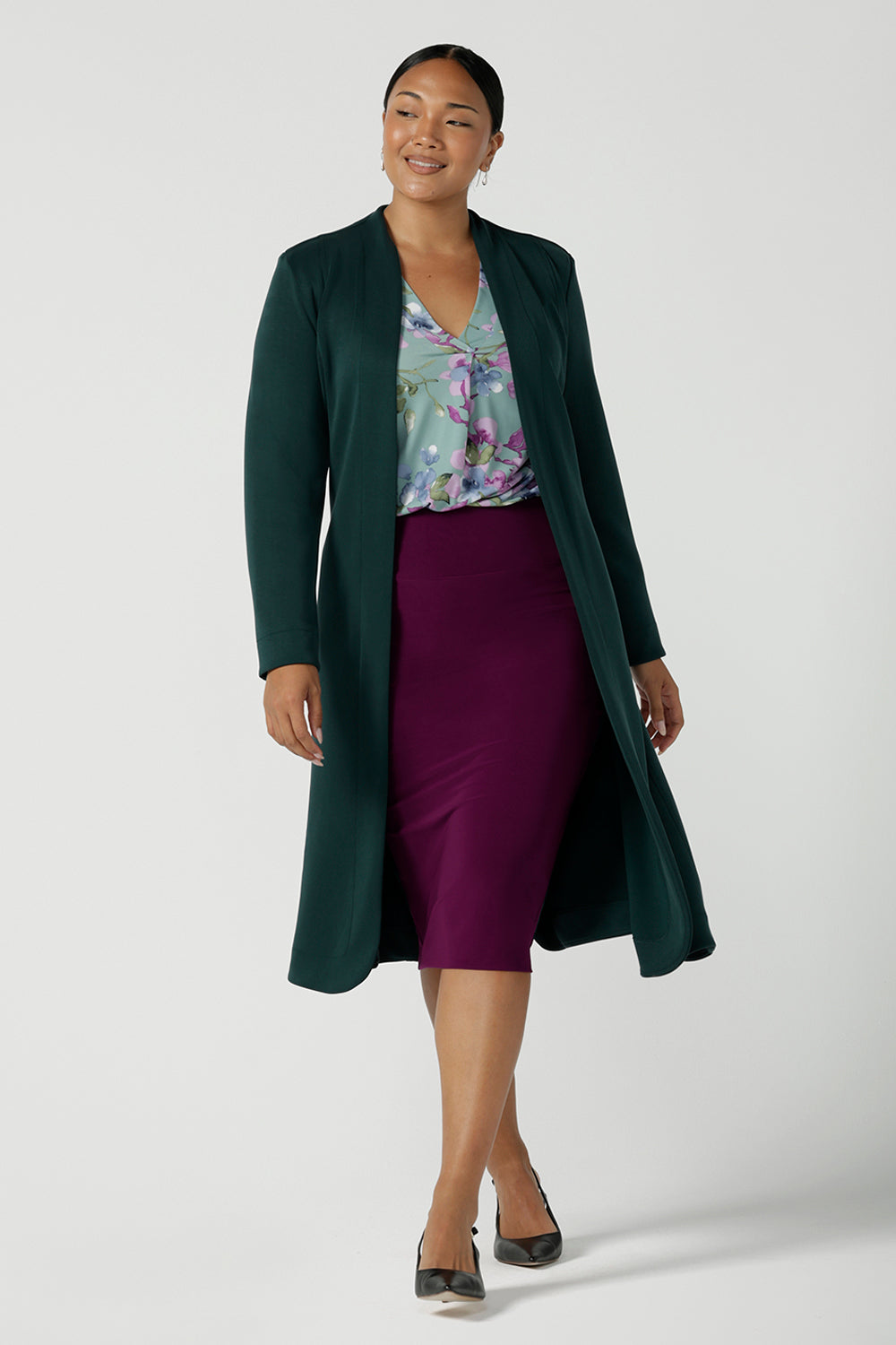 A size 10 woman wears the Andi skirt in Magenta. A made in Australia skirt styled back with the Paeton top in Day Bloom and the Sorel Trenchcoat in green. Size 8 - 24.