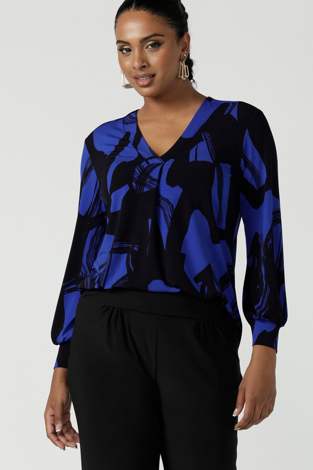 Woman wears the Paeton Top in Kabuki. A jersey v-neck style top with cuffed sleeve. Made in Australia for women size 8-24. Easy care work top for petite to plus size women.