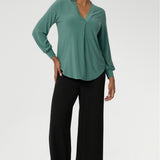 Finished with a curved shirttail hemline, the Paeton is ideal for workdays, weekend styling, and effortless layering. Available in sizes 8 to 24. Size 10 woman wears her Paeton Top in Menthol untucked over black wide leg trousers. 