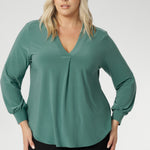 Designed with a relaxed fit that flatters all body types—petite to plus-size—you can easily size down for a more tailored silhouette. This chic top features a flattering V-neckline with a refined front tuck, long sleeves with cuffs, a shoulder yoke, and a centre-back tuck for subtle structure. Size 18 model wears her Paeton Top with black work pants. 
