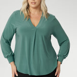 Designed with a relaxed fit that flatters all body types—petite to plus-size—you can easily size down for a more tailored silhouette. This chic top features a flattering V-neckline with a refined front tuck, long sleeves with cuffs, a shoulder yoke, and a centre-back tuck for subtle structure. Size 18 model wears her Paeton Top with black work pants. 