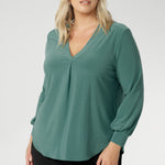 This chic top features a flattering V-neckline with a refined front tuck, long sleeves with cuffs, a shoulder yoke, and a centre-back tuck for subtle structure. Finished with a curved shirttail hemline, the Paeton is ideal for workdays, weekend styling, and effortless layering. Available in sizes 8 to 24