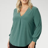 This chic top features a flattering V-neckline with a refined front tuck, long sleeves with cuffs, a shoulder yoke, and a centre-back tuck for subtle structure. Finished with a curved shirttail hemline, the Paeton is ideal for workdays, weekend styling, and effortless layering. Available in sizes 8 to 24