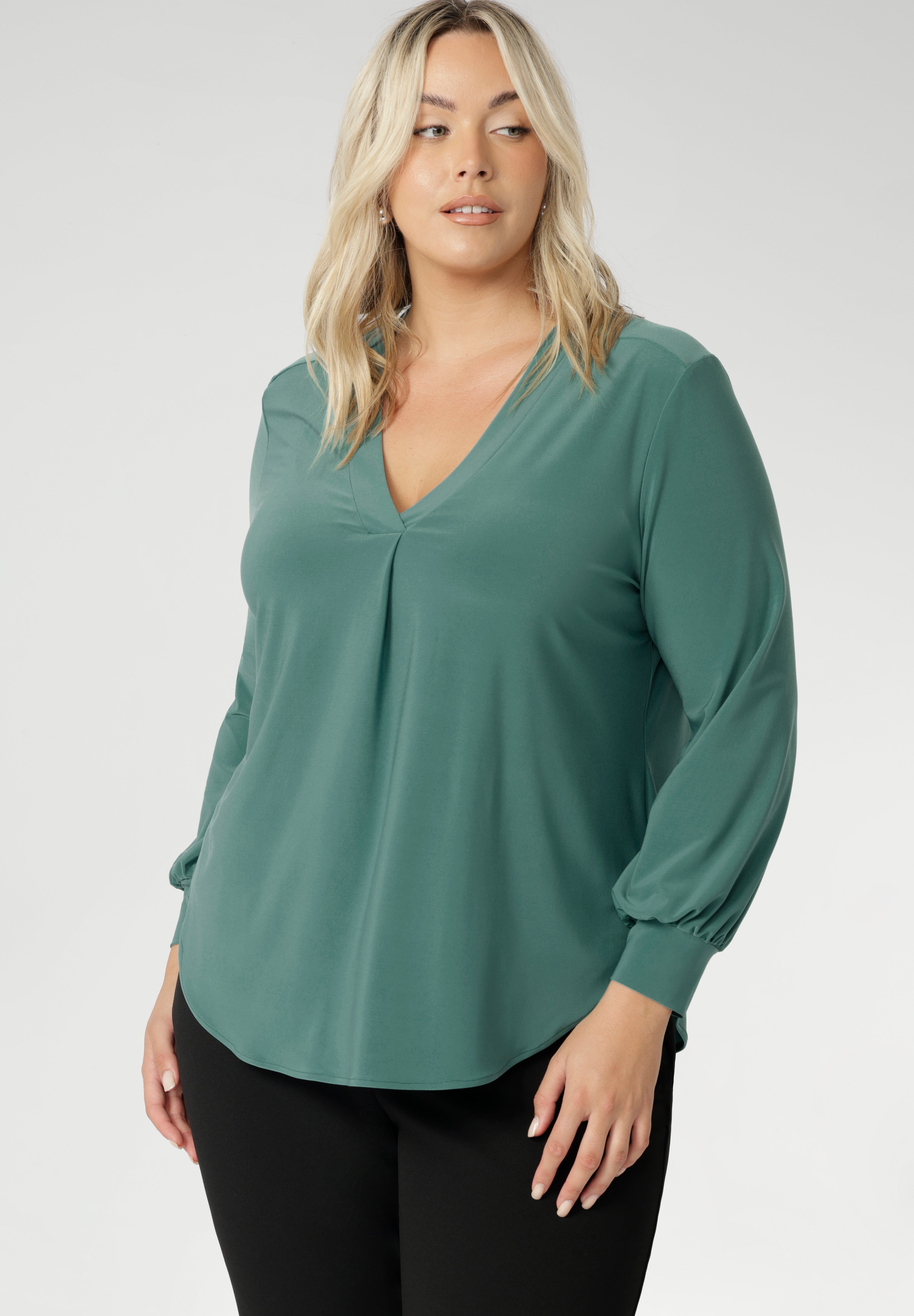 This chic top features a flattering V-neckline with a refined front tuck, long sleeves with cuffs, a shoulder yoke, and a centre-back tuck for subtle structure. Finished with a curved shirttail hemline, the Paeton is ideal for workdays, weekend styling, and effortless layering. Available in sizes 8 to 24