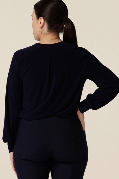 Back view of a woman wearing a V-neck, long sleeve jersey top in navy blue. Made in Australia by women's clothing label, Leina & Fleur, this great work top is available to shop online in sizes 8 to 24.