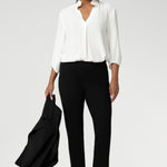 A size 10 woman wears the Paxton Pant in black. A loose fitting ponte pant in black. A slack pant with cropped length. Made in Australia for women size 8-24. Styled back with the Arley Top in white.