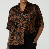 A woman wears the Pele Shirt in Bronze Animal,  a satin shirt with a relaxed dropped shoulder and fashionable leopard print animal design.  Made in Australia for women size 8-24. 