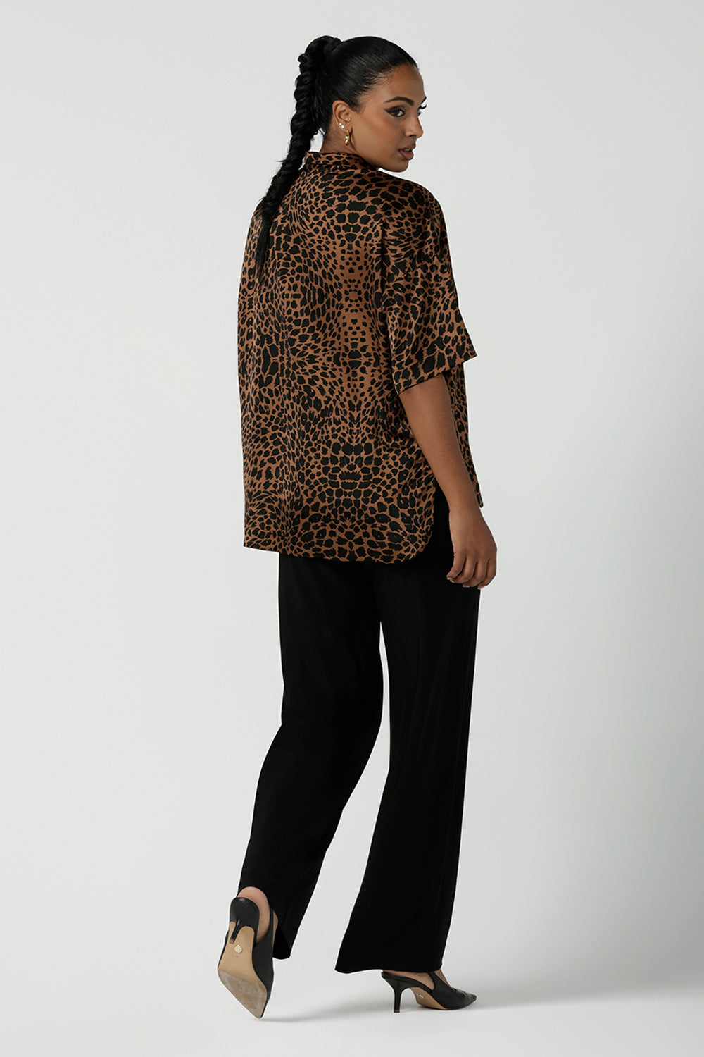 A back view of a woman wearing the Pele Shirt in Bronze Animal, a satin shirt with a relaxed dropped shoulder and fashionable leopard print animal design. Made in Australia for women size 8-24.