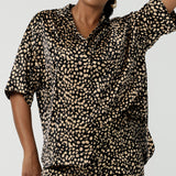 A woman wears the Pele Shirt in Animal print satin. A Australian made shirt with fashionable leopard print on a black base with vanilla spots. Made in Australia style for women petite to plus size 8-24.