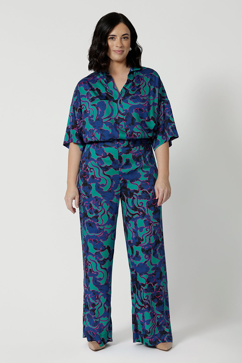 Full front image of a petite woman wearing a lightweight shirt that has above elbow-lengths and an abstract pattern. Made of comfortable satin rayon fabric displaying navy, pink and aqua blue colours. This Australian made house is breathable and made by Australian and New Zealand women. Leina and Fleur is a women’s clothing brand that proudly stocks sizes from 8 to 24 including plus & petite sizes. 