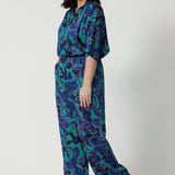 Image of a petite woman wearing a matching Jade Deco Shirt and pant set. This lightweight, above elbow-length shirt has and an abstract pattern displaying navy, pink and aqua blue colours. This Australian made shirt and pant set is made of satin rayon fabric that is breathable and comfortable. Leina & Fleur is a women’s clothing company that actively stocks plus & petite sizes ranging from 8 to 24.