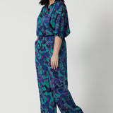 Full body shot image of a petite female model, wearing a matching light weight shirt and pant set. The abstract design of the set displays navy, pink and aqua blue colours. This Australian made shirt and pant set is made from satin rayon fabric that is breathable and comfortable. Leina and Fleur is a women’s clothing company that actively stocks plus sizes & petite sizes ranging from 8 to 24.