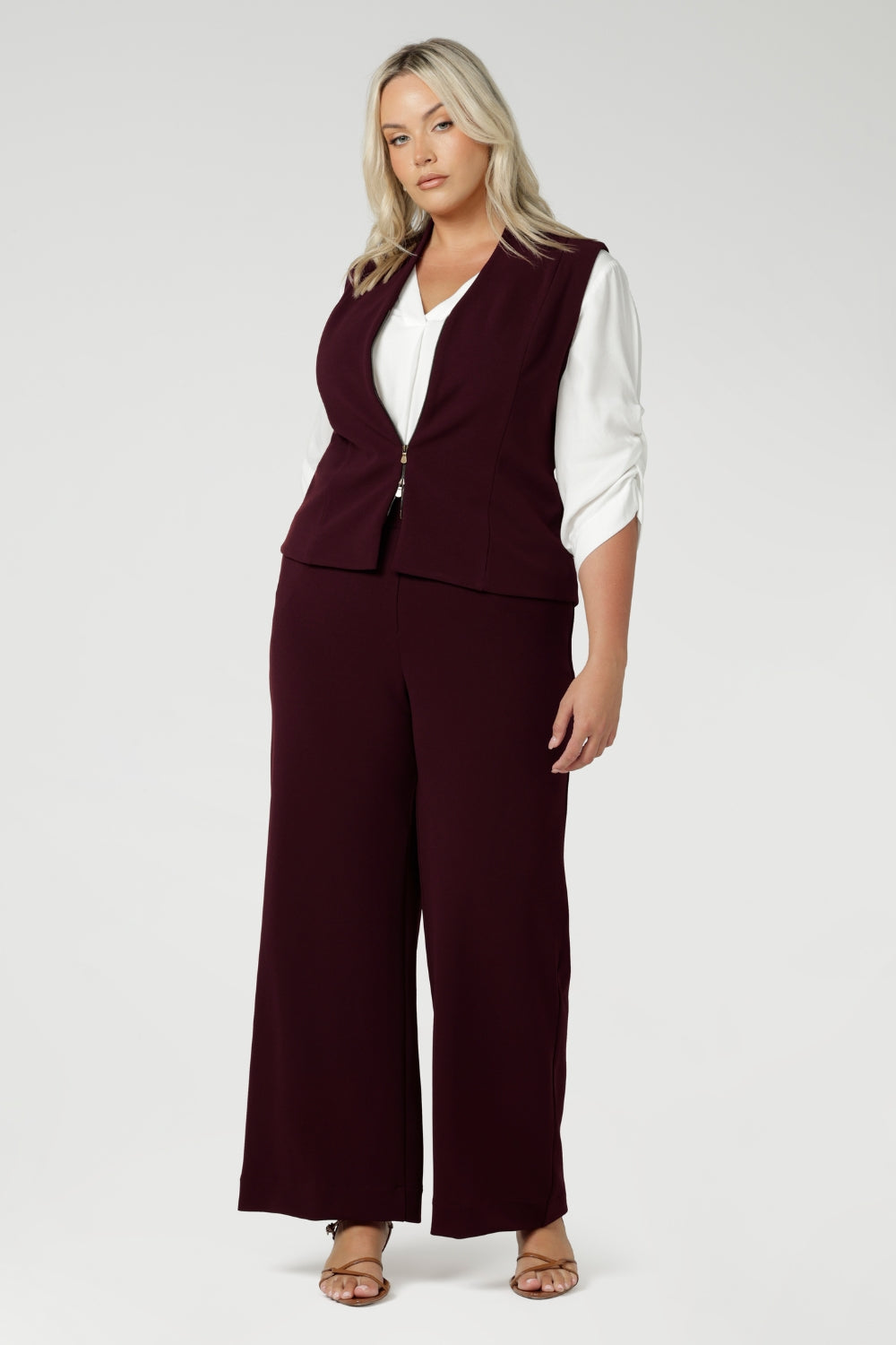 Available in sizes 8-24, this piece is proudly made in Australia by Leina & Fleur, combining both high-quality craftsmanship and contemporary style. Size 18 woman wears tailored vest with wide leg pants and white blouse.