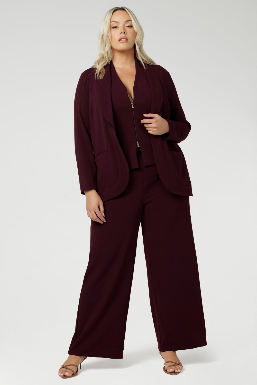 Size 18 woman wears 3 piece tailored suit. Australia made from light weight scuba crepe jersey. Woman's workwear blazer offers elevated style on its own or when paired with matching pants and vest. Size 18 woman wears workwear blazer suiting in deep wine colour. Womens workwear suiting offers full body stretch and comfort. Australia made by Leina & Fleur in sizes 8-24.