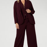 Size 18 woman wears 3 piece tailored suit. Australia made from light weight scuba crepe jersey. Woman's workwear blazer offers elevated style on its own or when paired with matching pants and vest. Size 18 woman wears workwear blazer suiting in deep wine colour. Womens workwear suiting offers full body stretch and comfort. Australia made by Leina & Fleur in sizes 8-24.