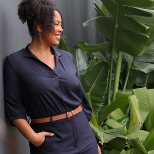 A banner image for a fashion blog on plus size clothing in Australia, a woman wears a plus size sustainable navy shirt and plus size tailored pants in navy.