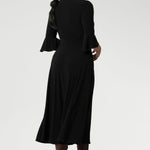 Back view of a size 10 corporate woman wears the Portia dress in Black. A wrap dress in black with tie side and 3/4 sleeve. Styled with long brown boots. Made in Australia for women size 8 - 24.