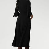 Back view of a size 10 corporate woman wears the Portia dress in Black. A wrap dress in black with tie side and 3/4 sleeve. Styled with long brown boots. Made in Australia for women size 8 - 24.
