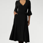 Size 10 corporate woman wears the Portia dress in Black. A wrap dress in black with tie side and 3/4 sleeve. Styled with long brown boots. Made in Australia for women size 8 - 24.