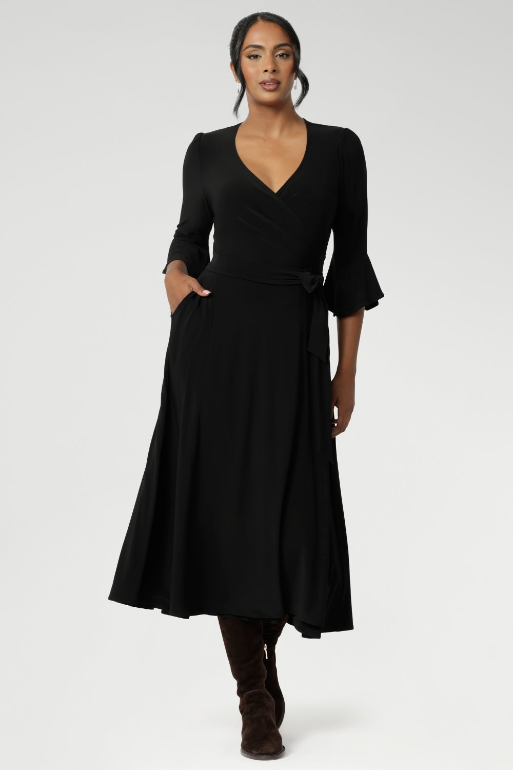 Size 10 corporate woman wears the Portia dress in Black. A wrap dress in black with tie side and 3/4 sleeve. Styled with long brown boots. Made in Australia for women size 8 - 24.
