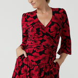 A size 10 woman wearing the size 10 Portia dress in Bold Poppy. Made in Australia for women size 8 - 24. A functioning wrap dress with waist ties and flutter sleeves.