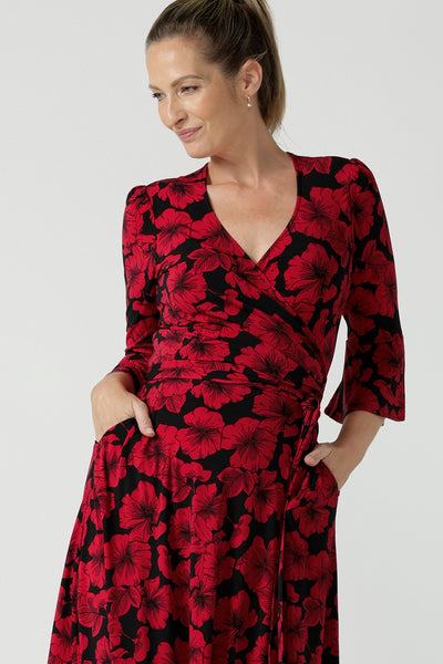 A size 10 woman wearing the size 10 Portia dress in Bold Poppy. Made in Australia for women size 8 - 24. A functioning wrap dress with waist ties and flutter sleeves.