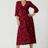 A size 10 woman wearing the size 10 Portia dress in Bold Poppy. Made in Australia for women size 8 - 24. A functioning wrap dress with waist ties and flutter sleeves.